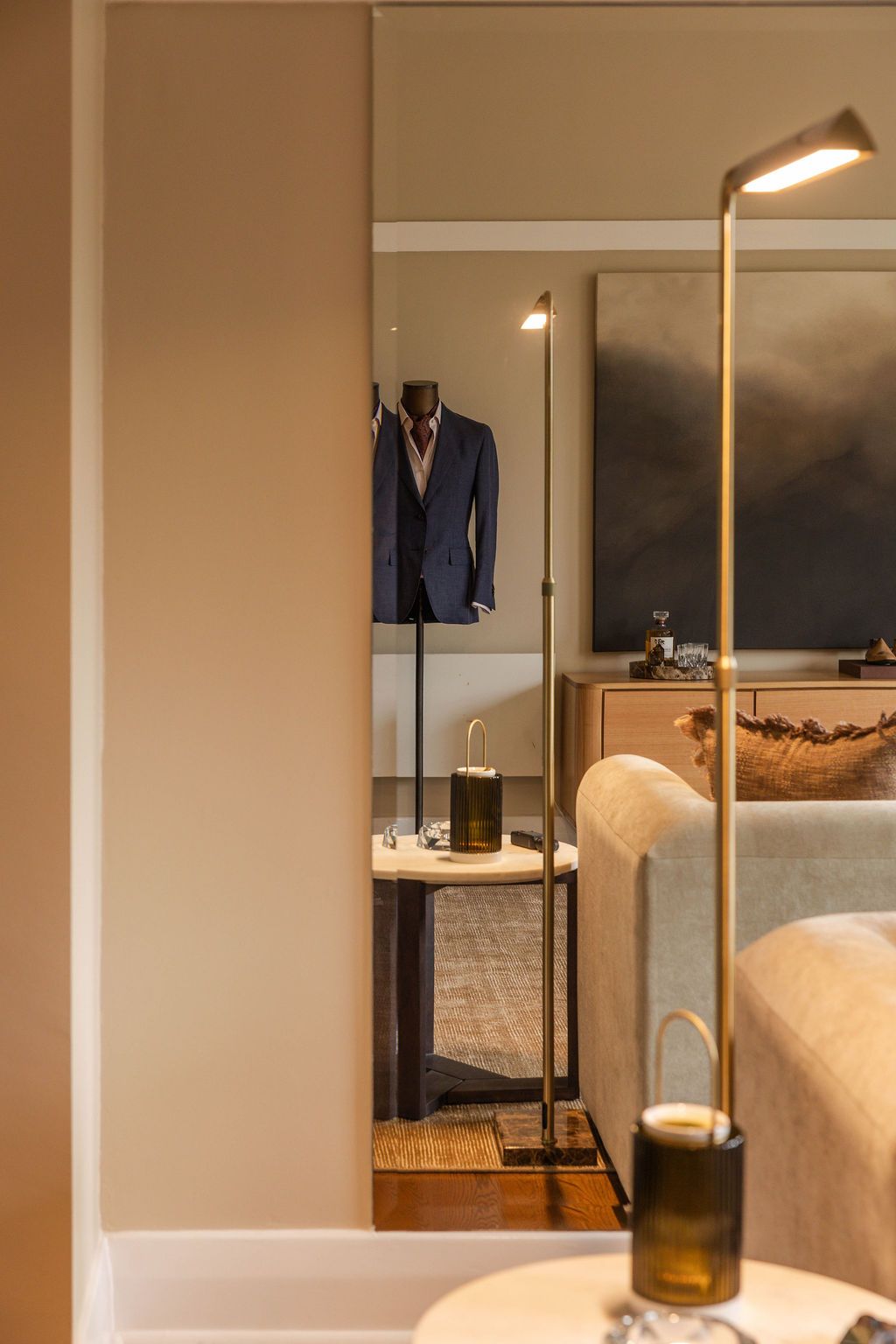 A suited mannequin seen through a mirror in the private Toorak showroom, an intimate setting under soft warm lighting