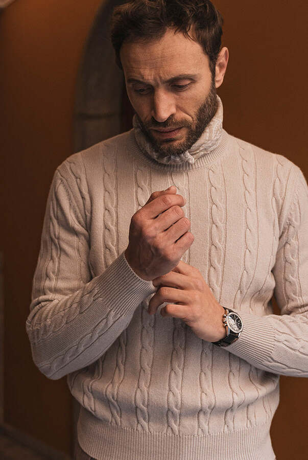 a man is wearing a patterned plain turtleneck sweater holding his cuff