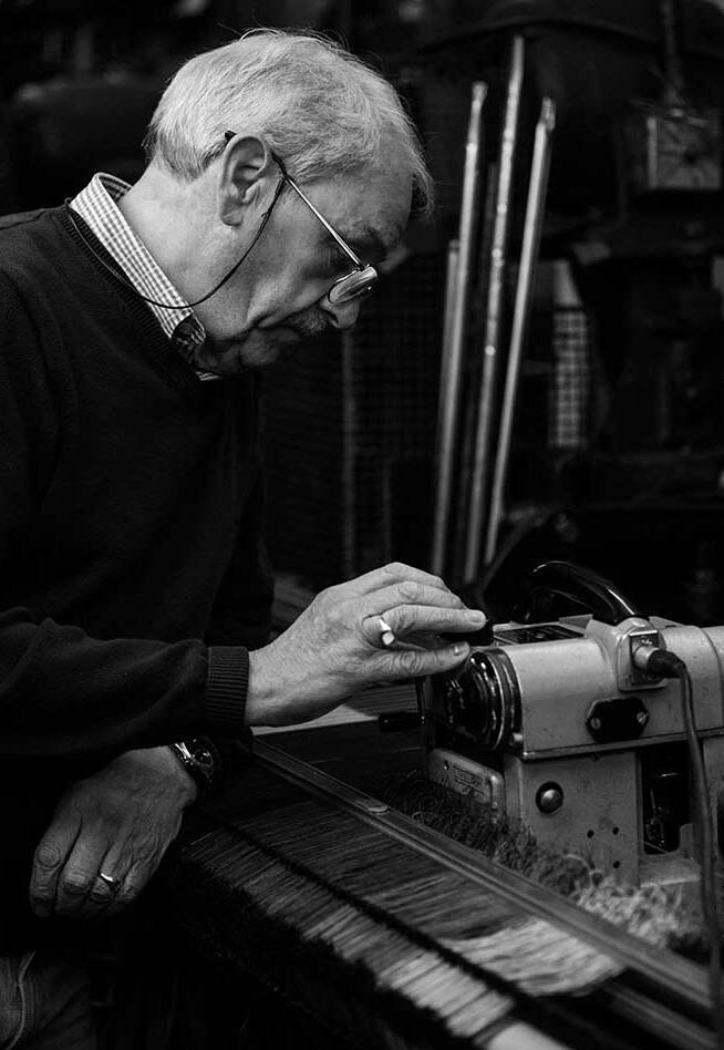 a black & white photo of a man operating a fabric machine