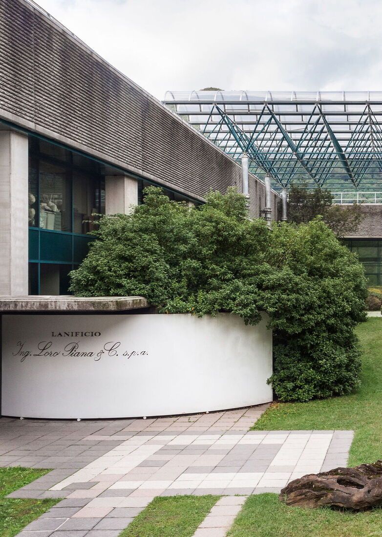Entrance of the Loro Piana mill surrounded by greenery and a landscaped yard