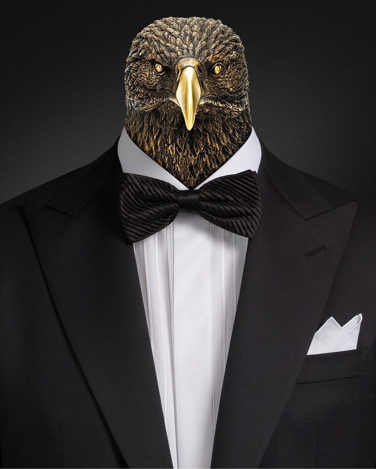 A bronze eagle head rising from the collar of a black dinner suit with a pleated silk bow tie and white pocket square