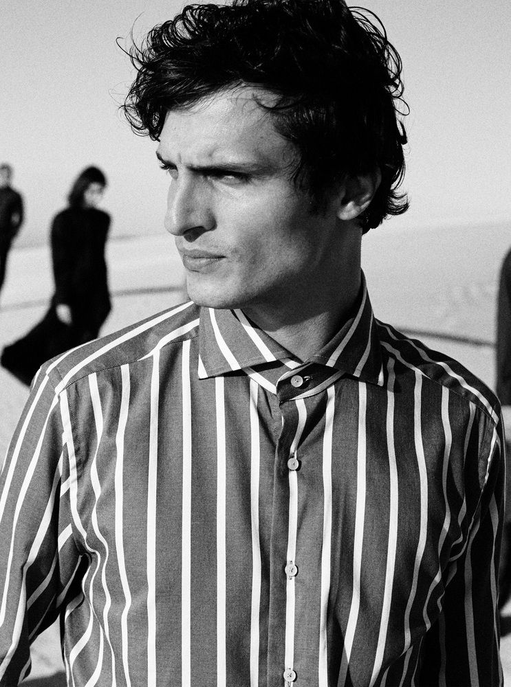 Black & white close-up of a man wearing a formal striped shirt looking to the side